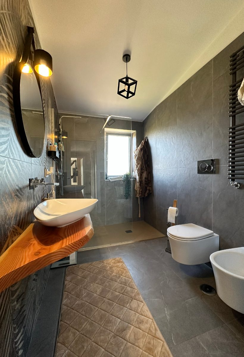 Bagno ristrutturato con rivestimento in gres scuro e vasca