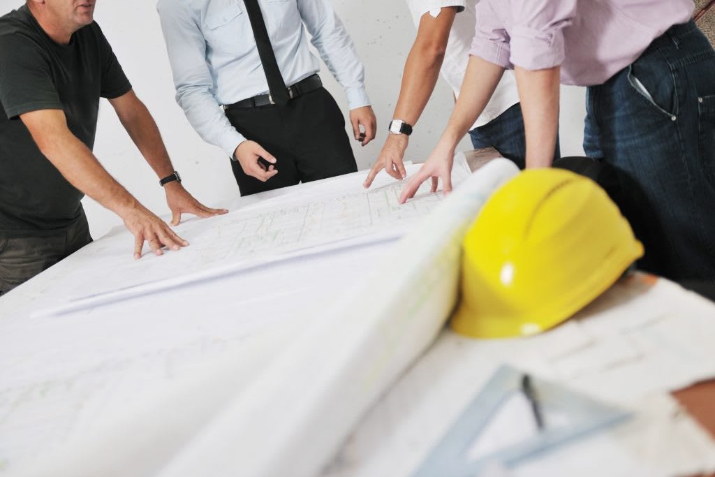 Progettisti e cliente a confronto sulla planimetria durante la progettazione di una ristrutturazione